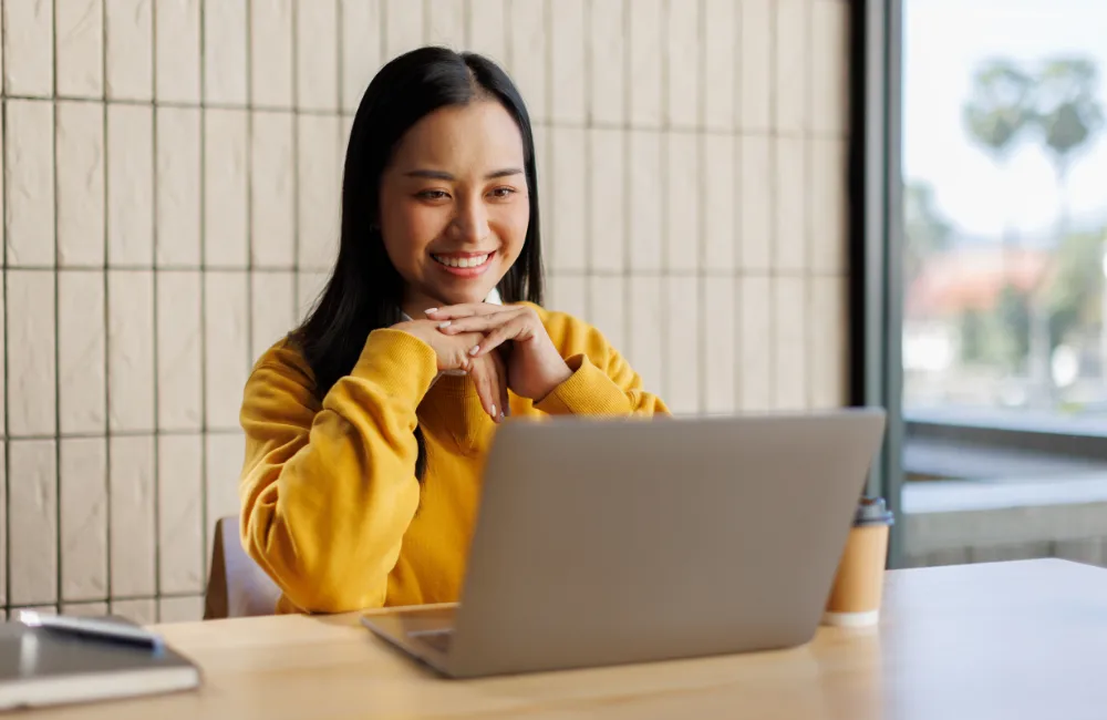 Happy woman at café using laptop