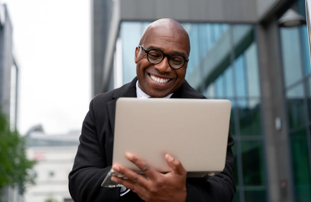Happy man outside holding laptop