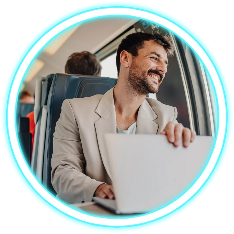 Man on train smiling and using laptop