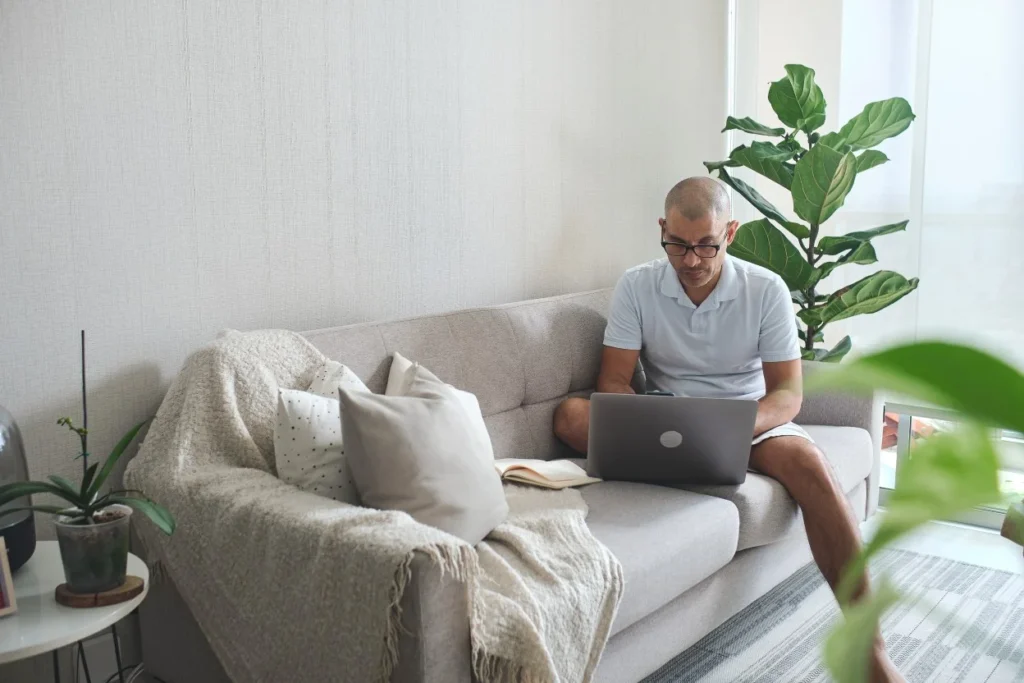 Man sitting on couch using laptop